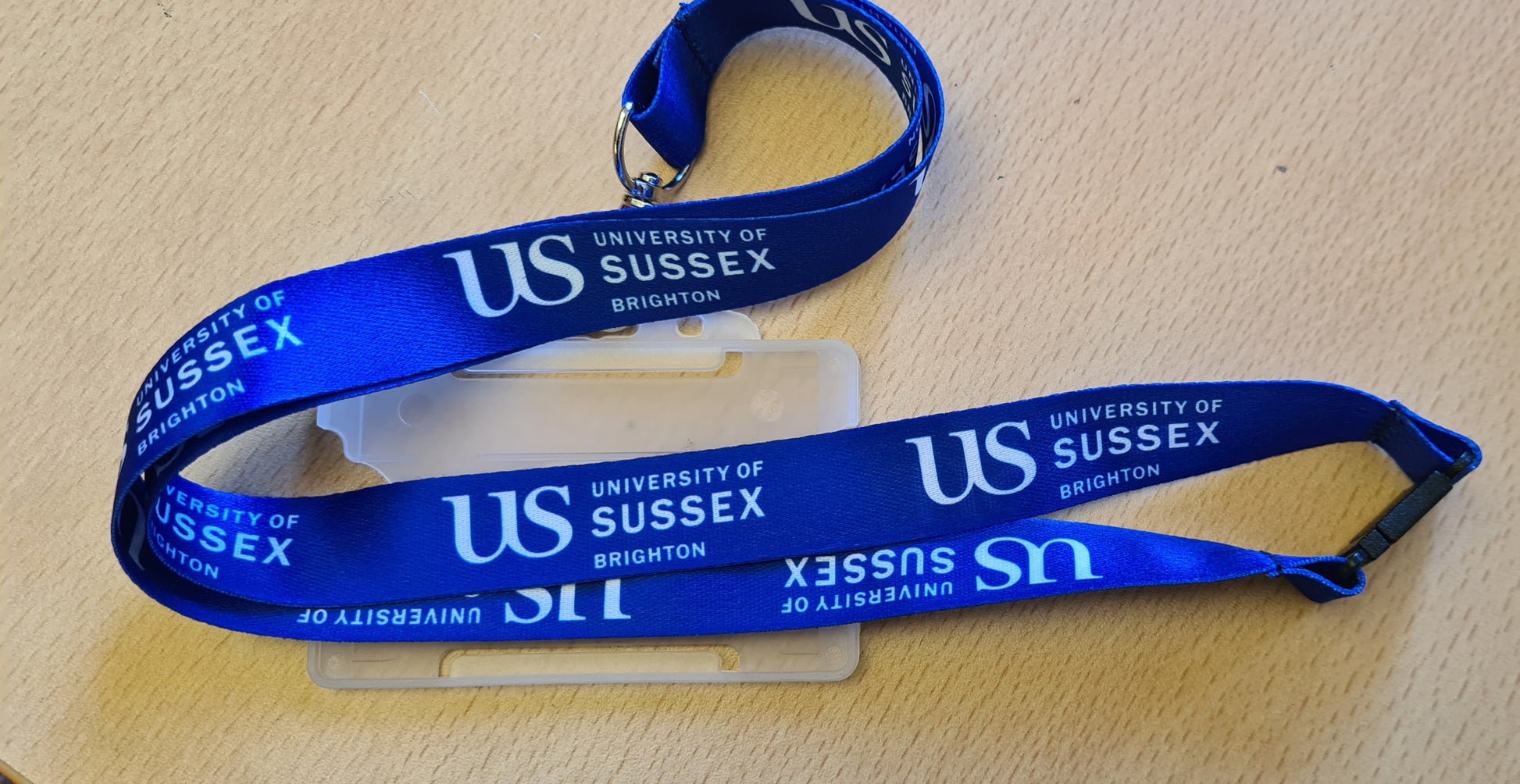 Blue lanyard with 'US University of Sussex' branding on a table