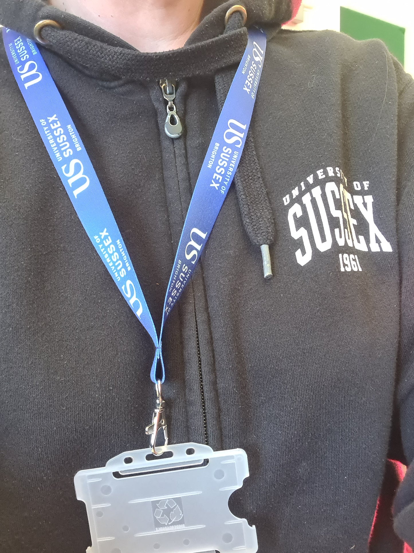 Person wearing a University of Sussex hoodie with a blue lanyard that says 'US University of Sussex' and a badge holder.